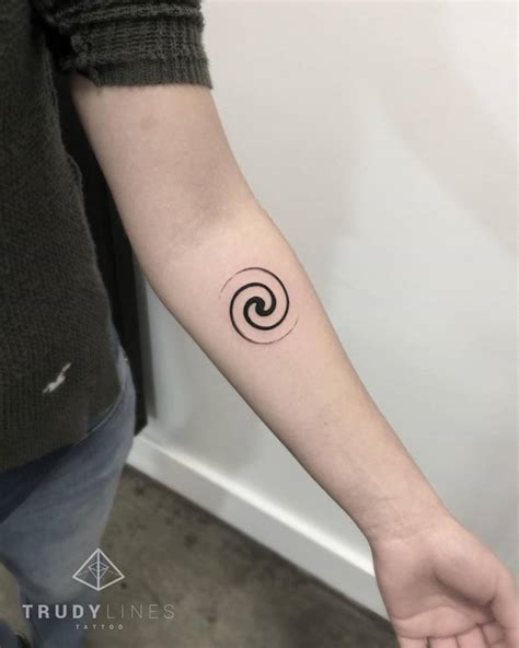 Small spiral tattoo on the left inner forearm.