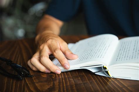 Crop unrecognizable man reading book at table · Free Stock Photo