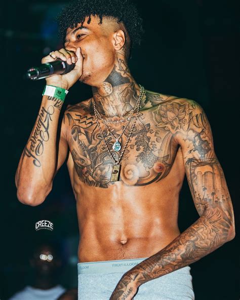 a man with tattoos on his chest holding a microphone