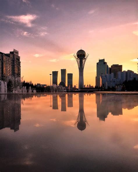 a city skyline is reflected in the water at sunset