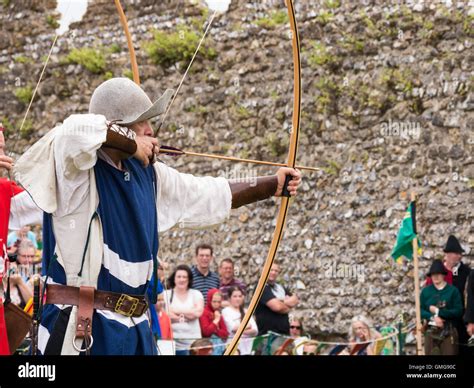 A medieval reenactor displays longbow archery techniques within the grounds of Portchester ...