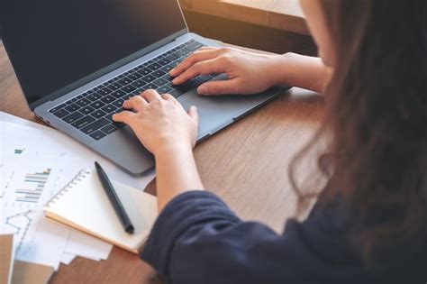 Mujer usando y escribiendo en la computadora portátil mientras trabaja ...