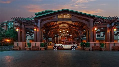 The covered entrance to an arts and crafts style hotel where an antique car awaits a … | Disney ...