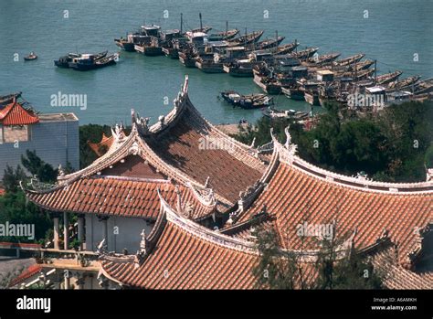 China, Fujian, Meizhou Island, gabled rooftops, with large group of fishing boats moored ...