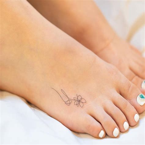 One line flower tattoo located on the foot.