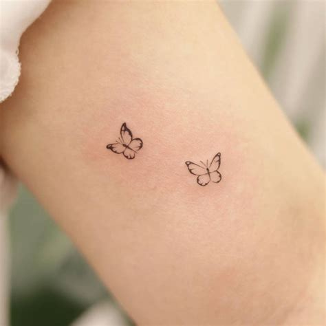 Fine line tiny butterflies tattoo on the bicep.