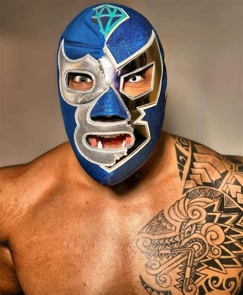 a man wearing a blue wrestling mask with tattoos on his arm and chest ...