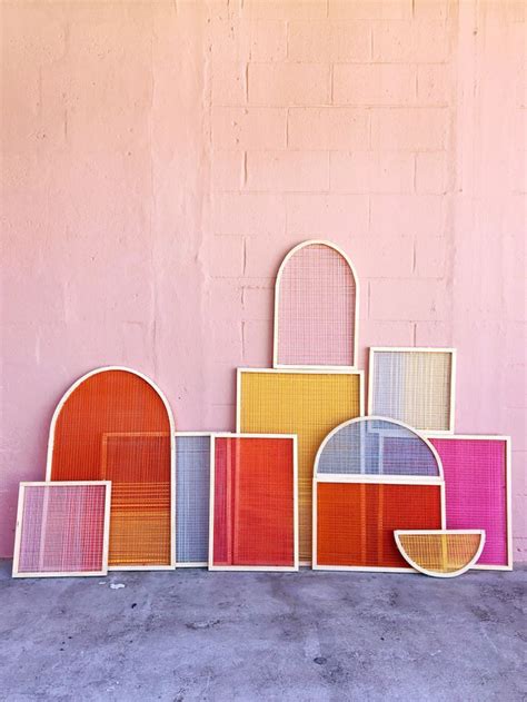 a group of different colored frames against a pink wall in front of a concrete floor