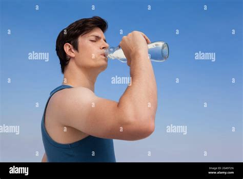 Man drinking water from bottle at beach Stock Photo - Alamy