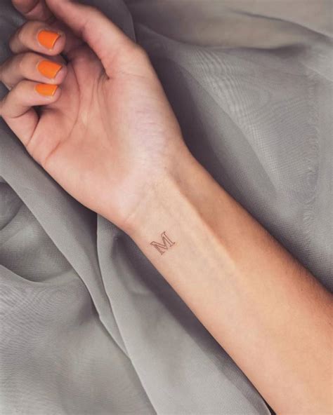 Tattoo of the letter "M" located on the wrist.