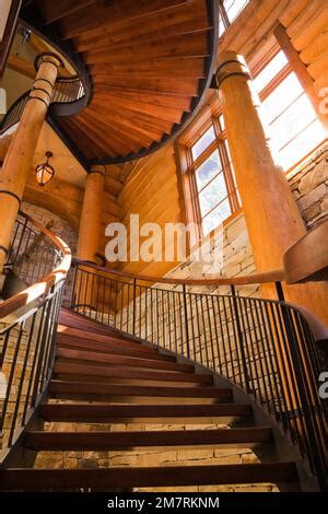 Curved and spiraling wood and wrought iron staircase leading to main floor inside luxurious ...