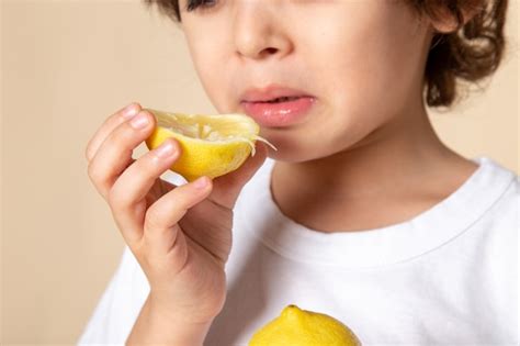 Free Photo | Close up, view cute kid eating sour lemon on pink