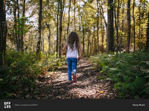 Young girl hiking through the woods on a trail stock photo - OFFSET