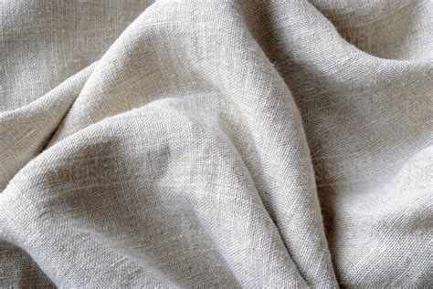 Gathered and folded texture of woven linen fabric with natural fibres in a close up full frame ...