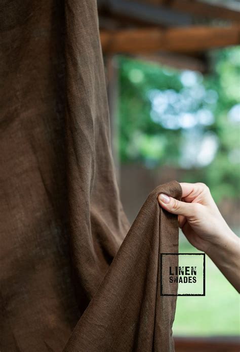 a person is holding the back of a brown curtain