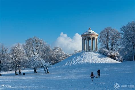 two people walking through the snow in front of a monument