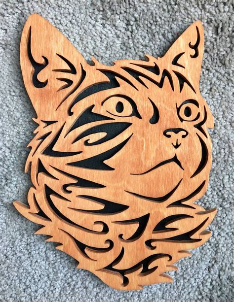 a wooden cutout of a cat's face on carpeted area with grey background