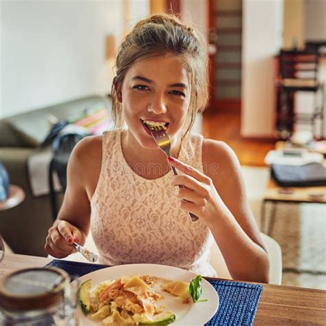Happy As Long As Im Not Hungry. Shot of a Young Woman Eating Food at the Dining Room Table at ...