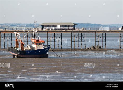 A fishing boat beached at low tide near the pier in Southend on Sea in ...