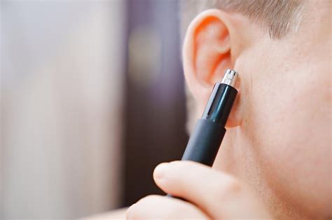 Premium Photo | Closeup a man cuts his ear hair with a trimmer