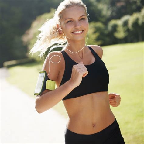 a woman running with headphones on her ears and wearing a black sports bra top