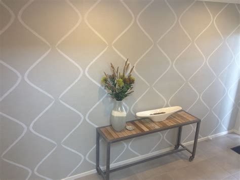 a vase with flowers sitting on top of a wooden table in front of a wall