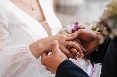 Premium Photo | The groom puts on the ring to the bride closeup exchange of rings