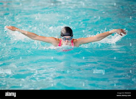 Young girl swimming butterfly stroke style in the blue water poo Stock Photo - Alamy