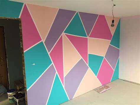 a room that has been painted with different colors and shapes on the wall, including triangles