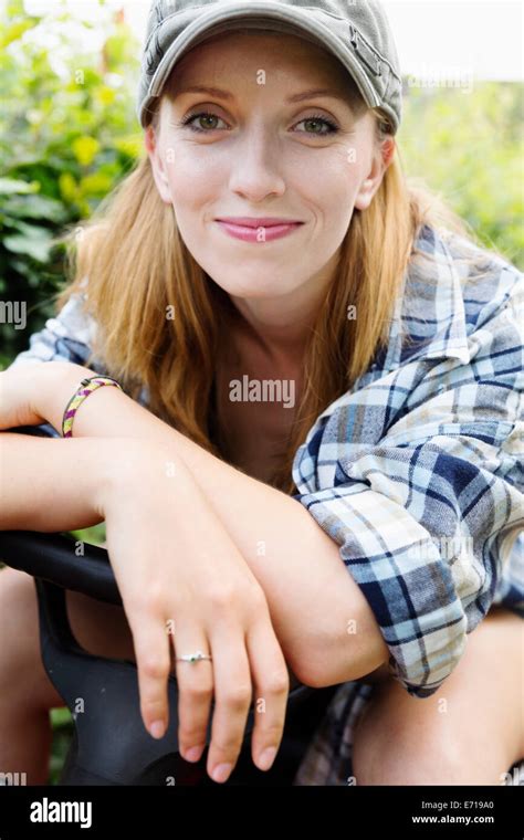 Portrait of a smiling young woman sitting on a lawn-mower Stock Photo - Alamy