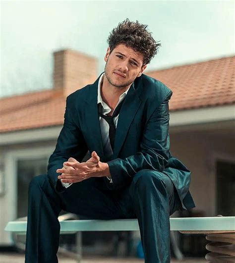 a man in a suit sitting on top of a metal table next to a building