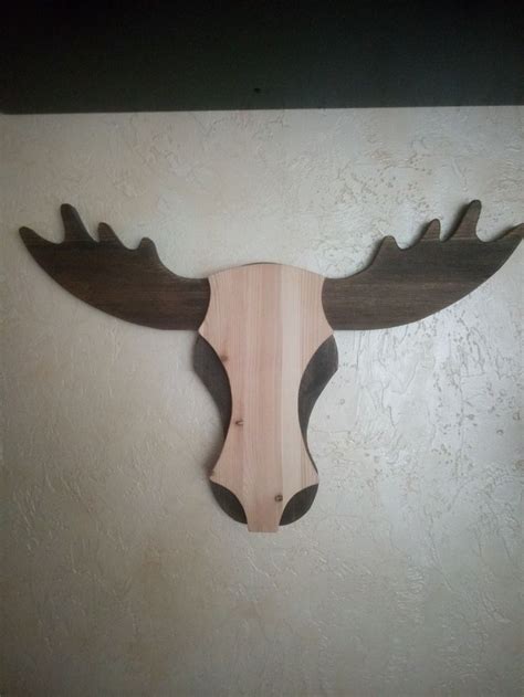 a wooden moose's head mounted to the side of a wall with antlers on it