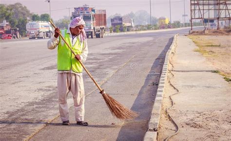 Sweeper cleaning the road with broom. A worker is working at site. He ...