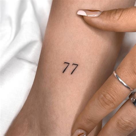 Number "77" tattooed on the inner arm.