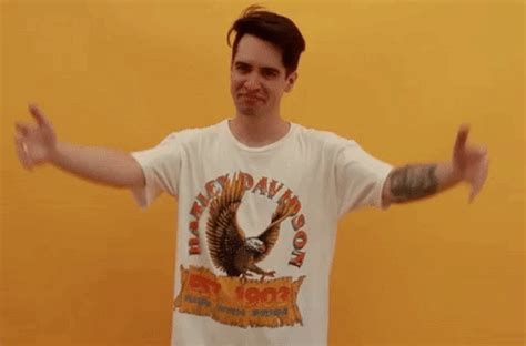 a man with his arms out in front of an orange wall and wearing a white t - shirt