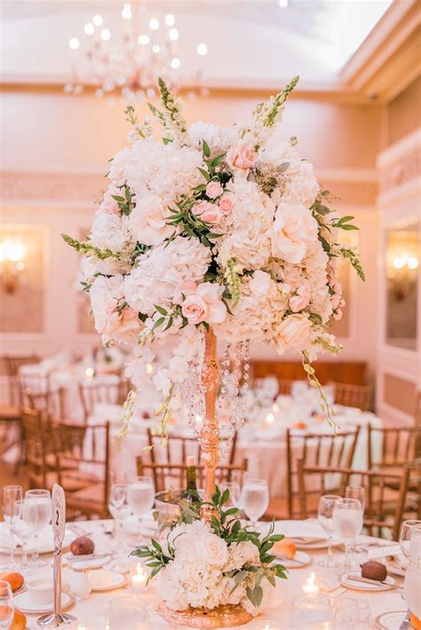 Beautiful elevated centerpiece on a gold candlestick with crystal drape. Flowers used are blush ...
