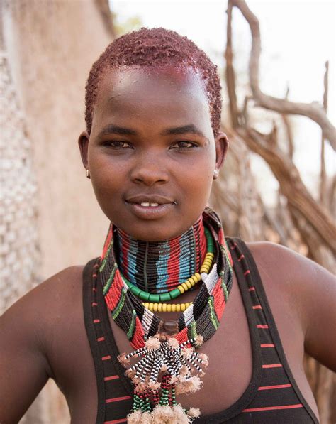 a woman with red hair wearing a multicolored necklace