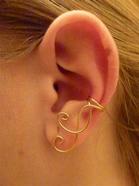 a close up of a person wearing a gold ear cuff