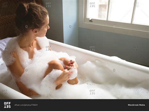 Woman taking a bath in bath tub at home stock photo - OFFSET