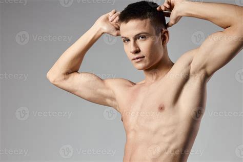 athlete with naked torso showing arm muscles on gray background cropped view of bodybuilder ...