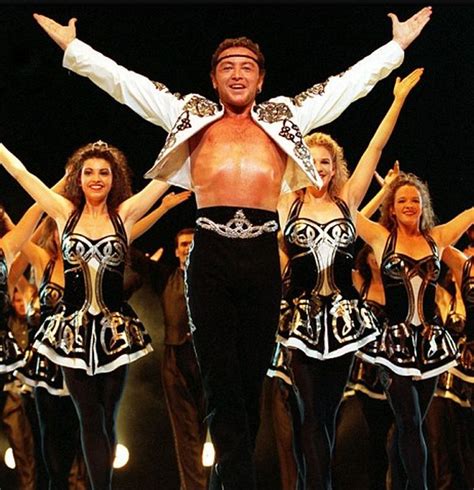 a man standing on top of a stage surrounded by dancers