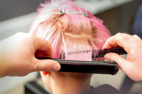 Premium Photo | Hairdresser straightening short pink hair