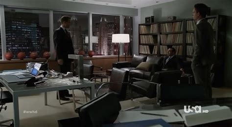 two men are standing in an office with desks, chairs and bookshelves