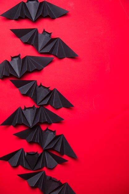 Premium Photo | Halloween bats made from paper on a red background