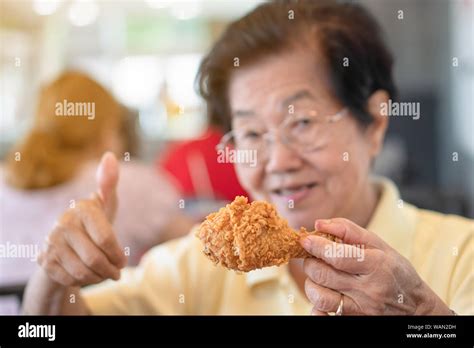 Selective focus of fried chicken, Asian elderly women are eating fried chicken. In the ...