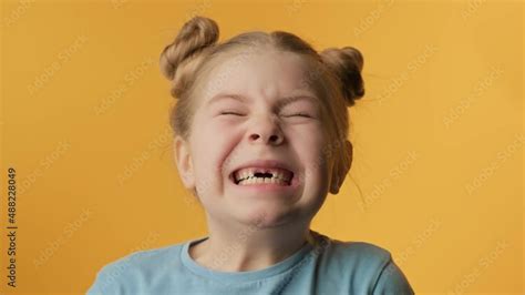 Portrait of little girl with toothless smile at yellow background ...