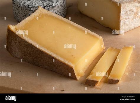 Piece of French Abondance cheese and slices on a cutting board close up Stock Photo - Alamy