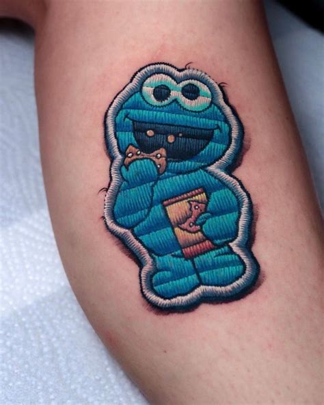 a blue cartoon character tattoo on the right arm and leg, with a book in his lap