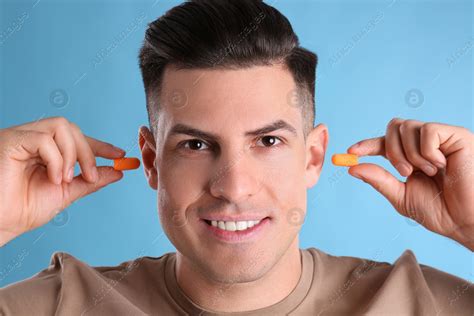 Man inserting foam ear plugs on light blue background: Stock Photo | Download on Africa Images ...