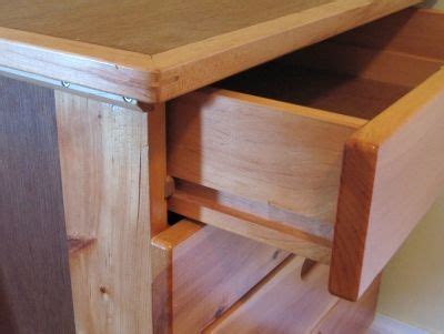 a close up of a wooden cabinet with drawers on the bottom and one drawer open